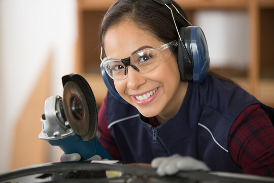 smiling female worker using angle grinder - Powered by Adobe