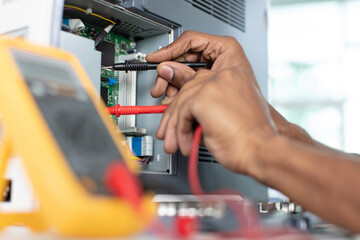 hands measuring the voltage of computer board