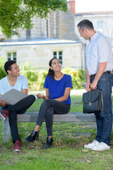 Fototapeta premium school teacher reviewing exercises with teenagers outside school