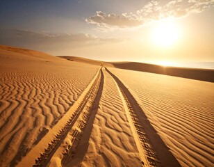 Tire tracks on desert sand dunes at sunset