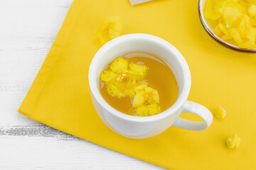 Cup of herbal tea with mullein flowers and leaves on neutral wooden background. Natural light