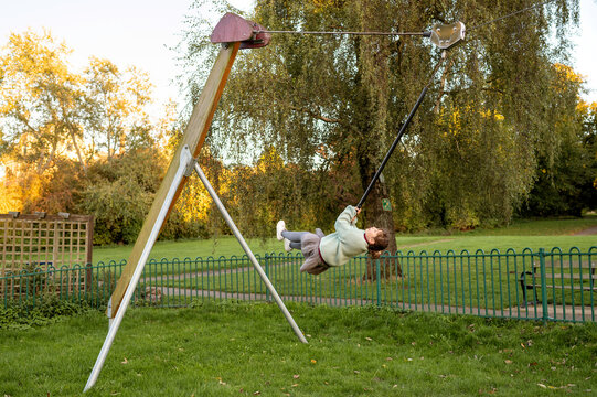 Girl enjoying ride on playground zip line swinglocal