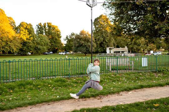 Young girl swinging on zip-line swing on playground.