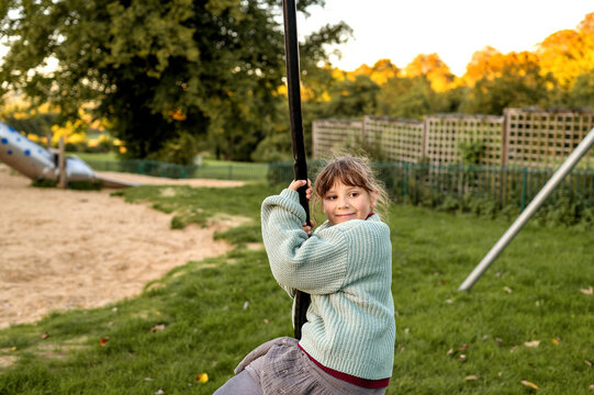Young girl ridding at ropeway on playground.