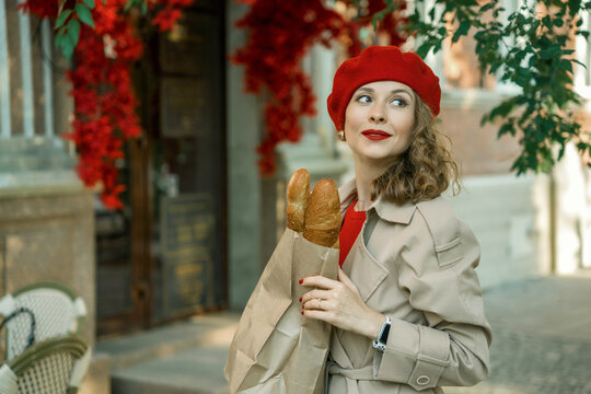 A stylish woman in a beige raincoat and a red beret with baguettes