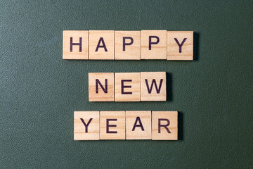 Wooden letter tiles spelling Happy New Year arranged neatly on a textured green background