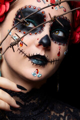 Halloween beauty portrait of woman. Female face adorned with Santa Muerte makeup and covered with barbed wire.