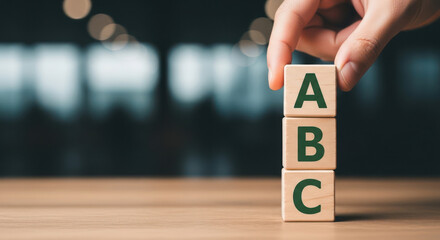 Hand stacking wooden blocks abc representing business basics learning and development