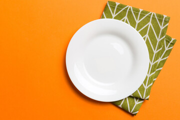 Top view on colored background empty round white plate on tablecloth for food. Empty dish on napkin...