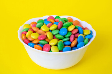 Multicolored candies in a bowl on a colored background. birthday and holiday concept. Top view with copy space