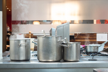 Professional kitchen preparing food with steaming pots on stove