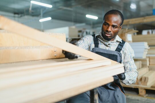 African american Carpenter checking wooden planks in furniture factory