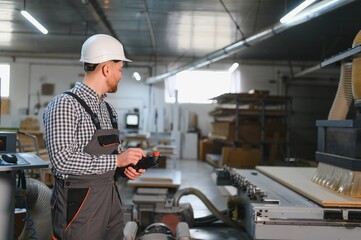 Carpenter operating cnc machine in furniture factory