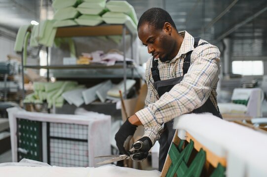 African american Furniture maker cutting fabric in a furniture factory