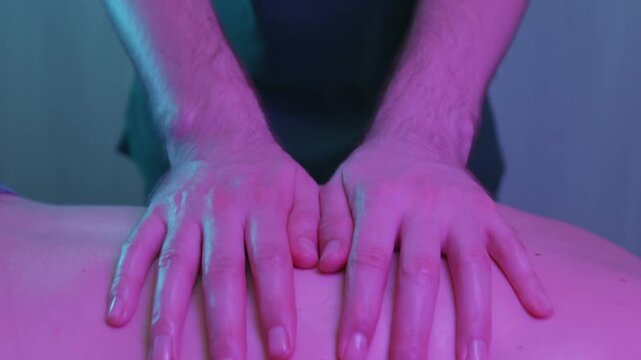 Massage in clinic - a man therapist massaging bare back of a female client