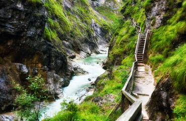 Lammerklamm Gorge in Salzkammergut region of Upper Austria. Blue alpine river between narrow rocky cliffs covered with green vegetation and trees. Scheffau am Tennengebirge