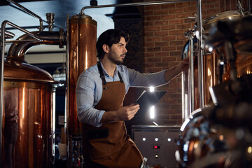 A brewer man worker wearing an apron is diligently working in a local brewery