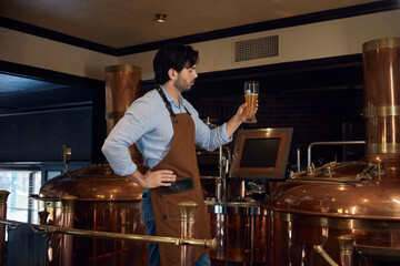 A man is taking in the aroma of a glass of beer in a brewery