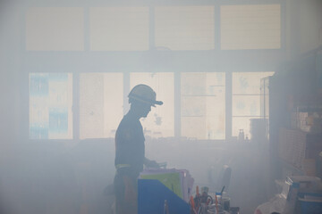 Firefighter in fire smoke extinguishing approach in office