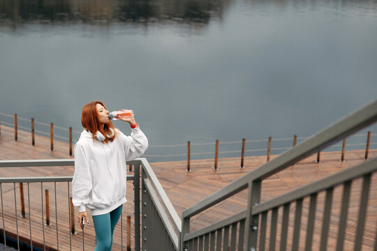Woman drinking water at wooden pier after hard training