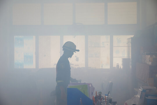 Firefighter in fire smoke extinguishing approach in office