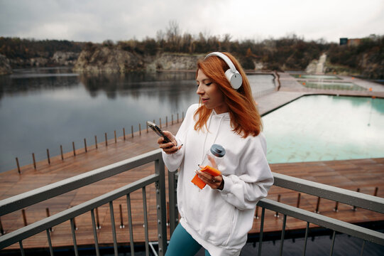 Woman in headphones listening music and browsing mobile phone