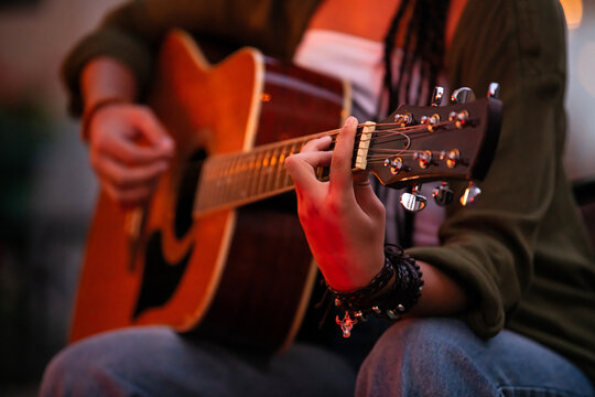 girl plays an acoustic guitar, plucking the strings