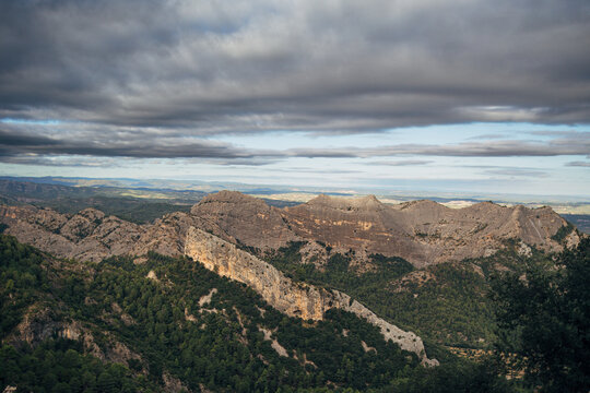 Dramatic mountain landscape with vibrant green forest and cloudy sky