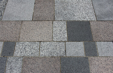 Texture of gray, white, black, and brown square paving tile. Pattern of sidewalk tiles in the street. Concrete pavers close up background.