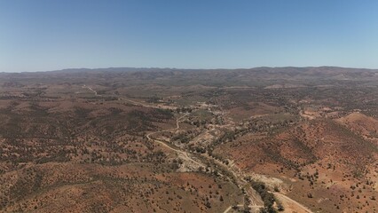 Fototapeta premium Brachina Gorge, South Australia – Aerial Drone Image of Geological Trail, Rugged Red Cliffs, Winding Dirt Road, Vast Valleys, Mountain Ridges, Rocky Terrain, Outback Landscape in Flinders Ranges