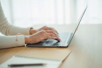 Close-up of Hands Typing on a Laptop Keyboard in a Bright and Modern Workspace with Natural Light Filtering through Window