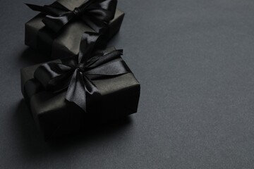 Black Friday. Top view of black gift boxes tied with ribbons,  on a dark backdrop, providing space for your message or promotion