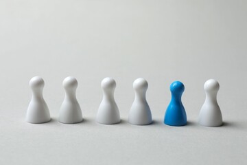 Color pawn among white ones on the table. The concept of difference and uniqueness