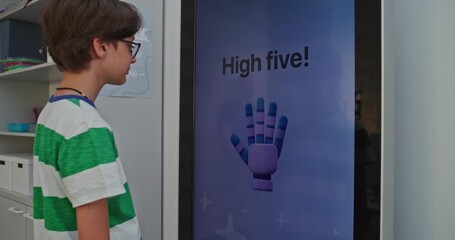 Close up of Schoolboy Wearing Glasses Happily Communicating With AI Mood Tracker. Kids Show Positive Emotions During Learning. Concept of Educational Technologies, Developing Emotional Intelligence.