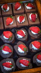 Chocolate cupcakes and mini cakes topped with strawberries and cream