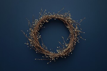A circular, rustic wreath composed of dried twigs and tiny, light-colored beads, displayed against a rich navy blue backdrop.
