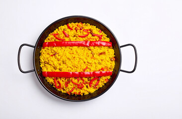 Paellera vista desde arriba con arroz amarillo y tiras de pimiento rojo sobre fondo blanco, en los colores de la bandera de España. Fotografía gastronómica minimalista por el Día de la Hispanidad