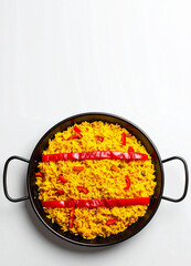 Paellera vista cenital con arroz paella amarillo y tiras de pimiento rojo sobre fondo blanco, colores de la bandera de España. Fotografía de gastronomía española por el Día de la Hispanidad