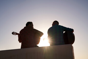 Two flamenco guitarists playing and enjoying a sunset artistic moment outdoors, sharing music and passion