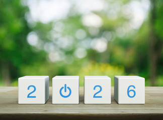 2026 start up business icon on white block cubes on wooden table over blur green tree in park, Happy new year 2026 success concept