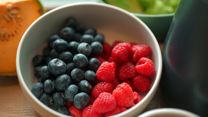 Close up of fresh blueberries and raspberries in a white bowl