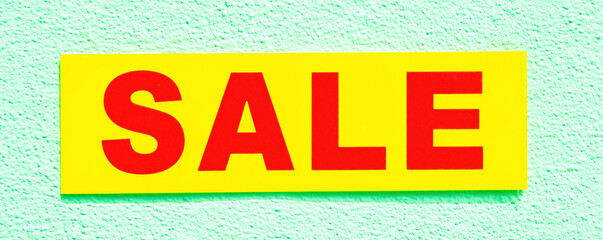 Naklejka premium Bright yellow sale banner displayed on a blue wall invites customers to shop during seasonal discounts