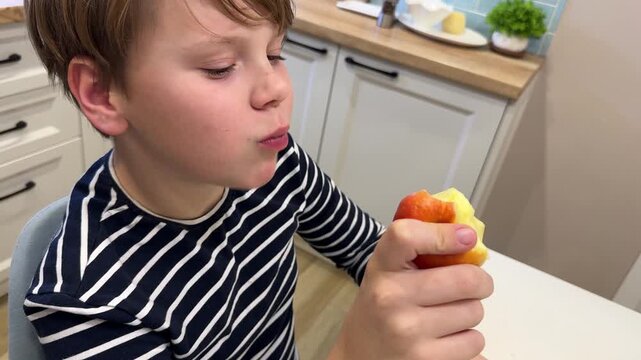 A teenager holds an apple to his face. Close-up.