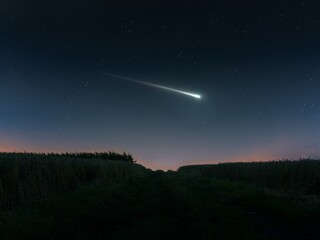 Fireball in the evening sky over the fields. Bright shooting star. Meteor illuminates the starry sky.