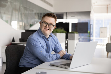 Positive Caucasian business professional man with Down syndrome using laptop © fizkes