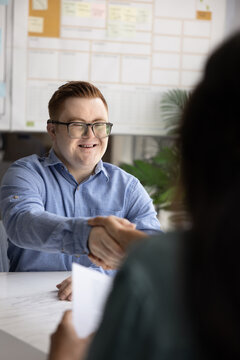Positive employee with Down syndrome giving handshake to female employer