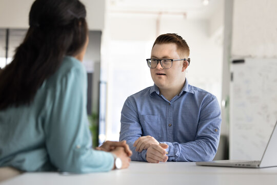 Positive professional man with Down syndrome talking to female colleague