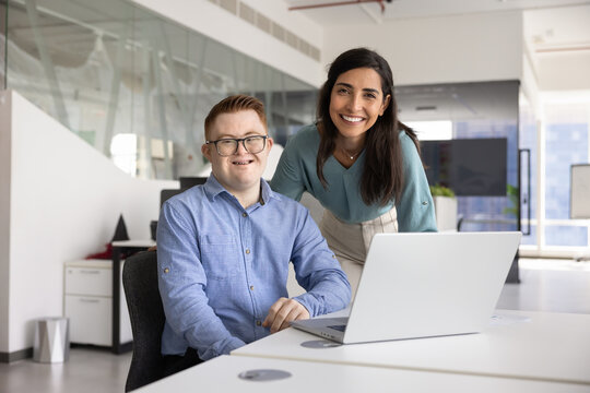 Mentor woman working with young employee man with Down syndrome - Powered by Adobe