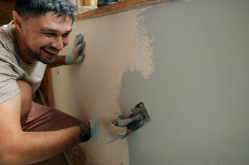 Handyman plastering interior house wall during renovation