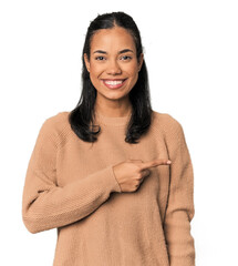 Young Filipina woman smiling and pointing aside, showing something at blank space.